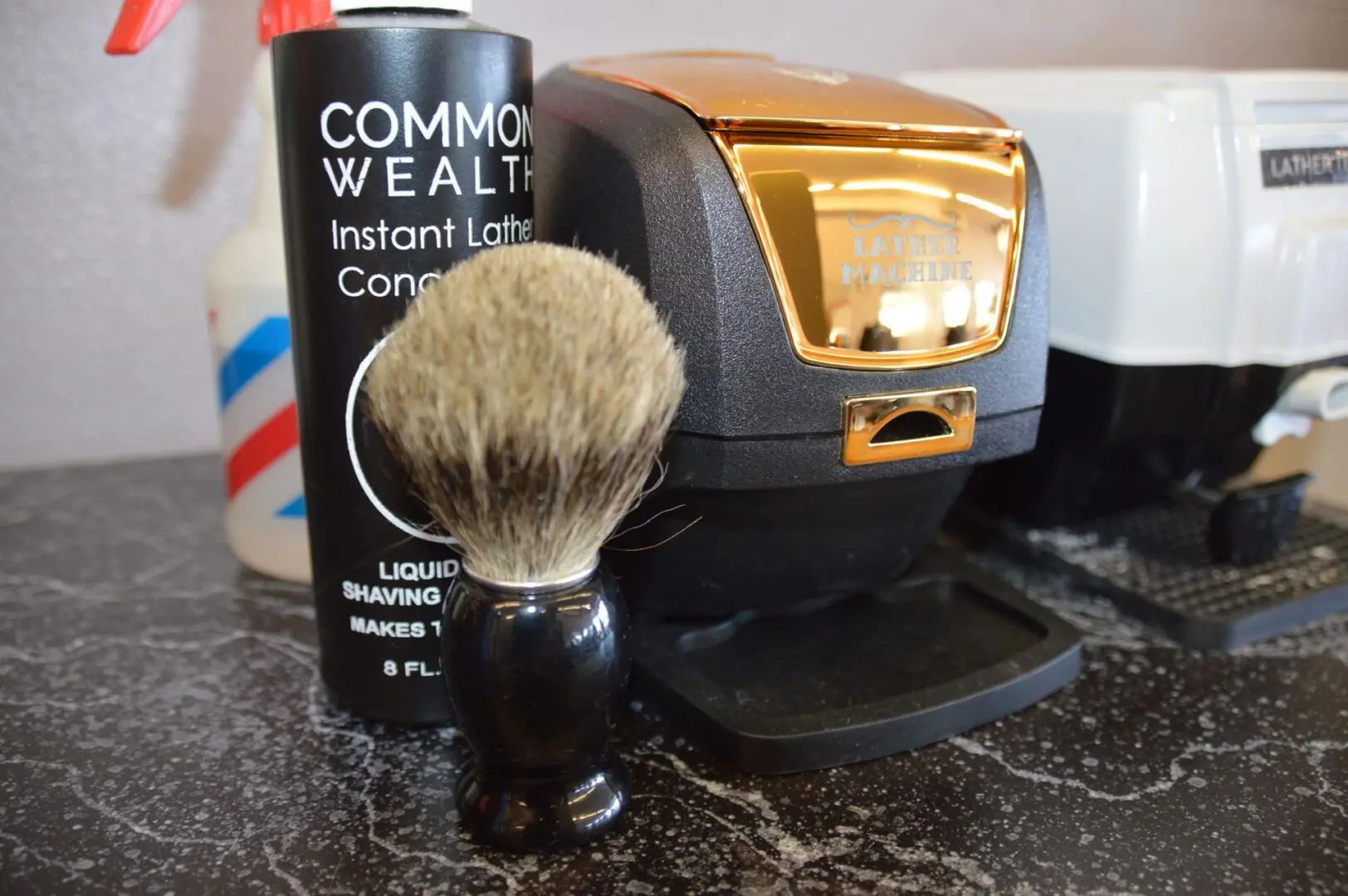 A black and gold shaving brush next to a razor.